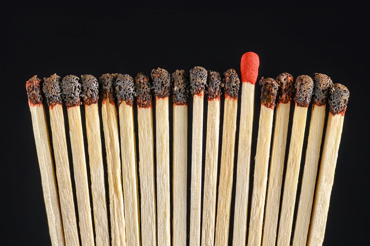 A group of burnt matchsticks with one untouched, symbolizing uniqueness and distinction.
